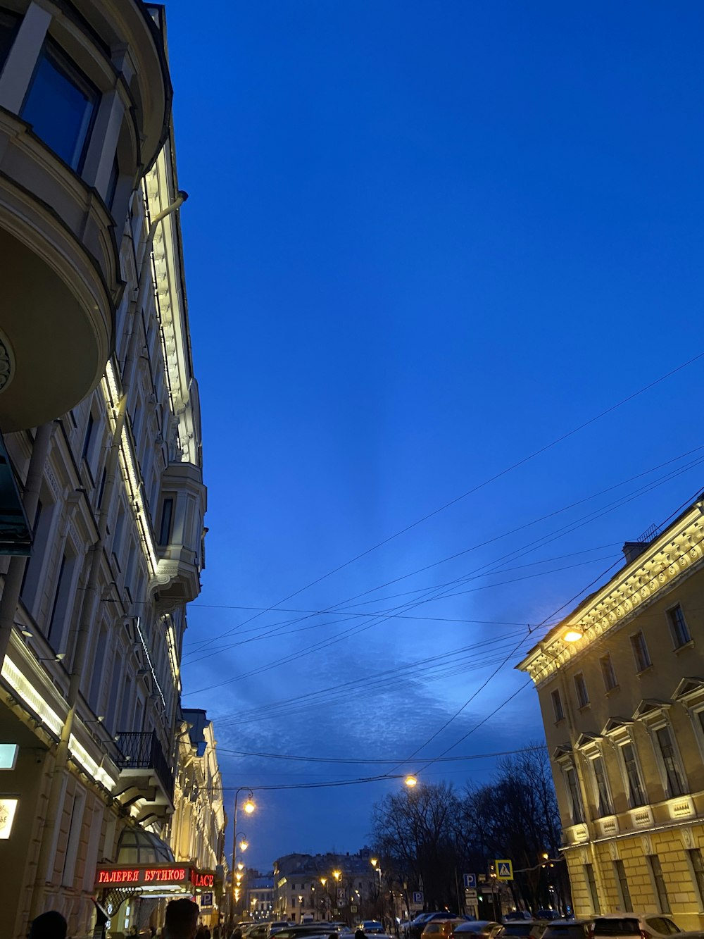 a city street at night with cars parked on the side of the street