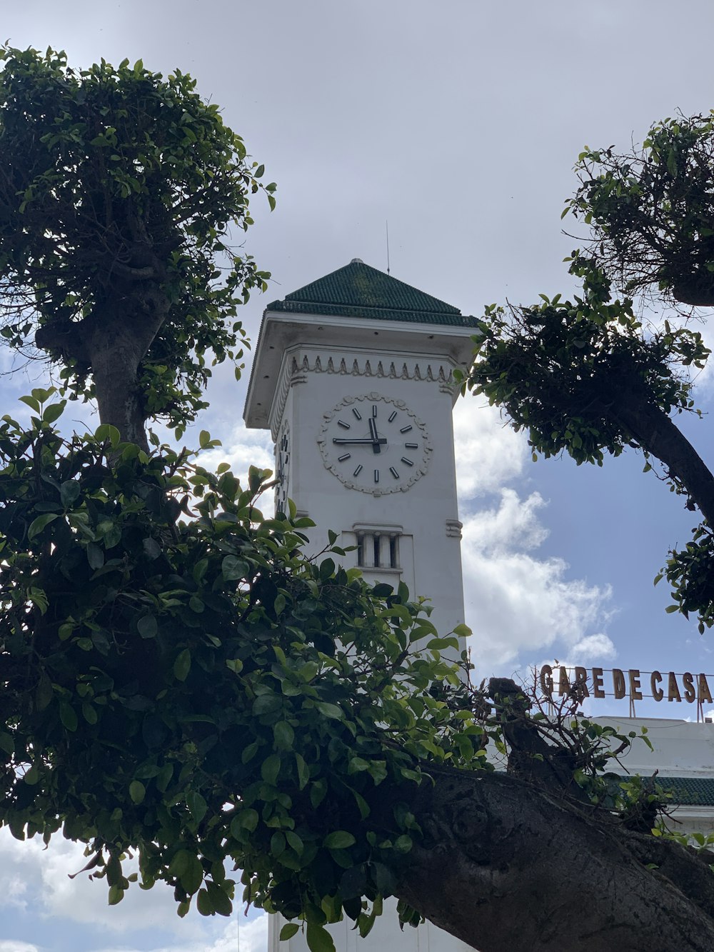 a white clock tower with a green roof
