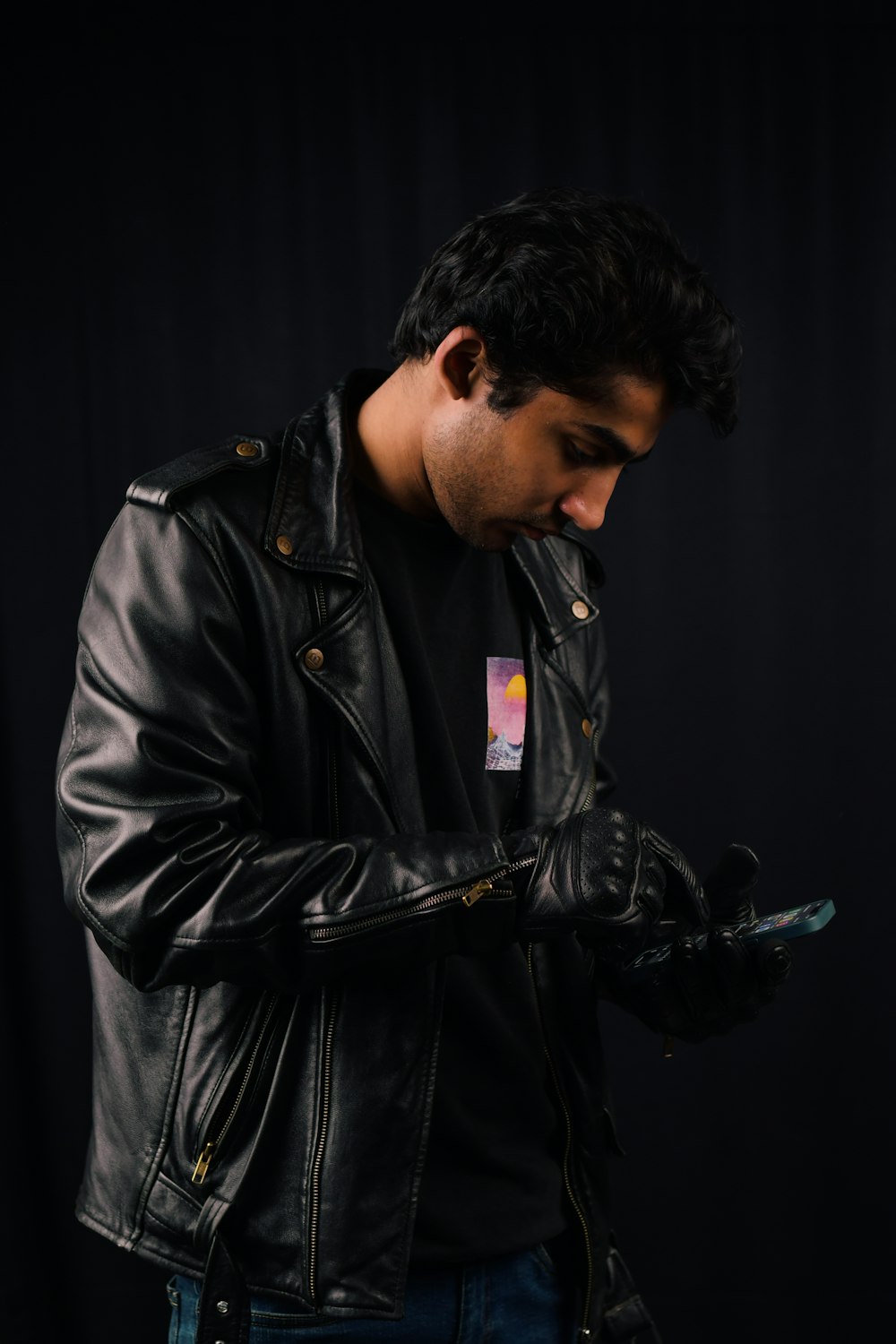 a man in a black leather jacket holding a cell phone