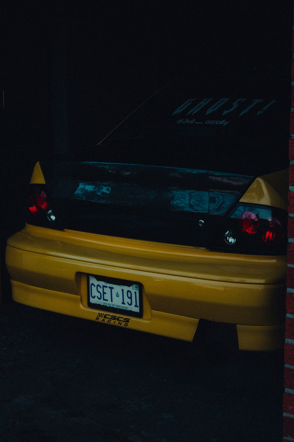the back end of a yellow car parked in a garage