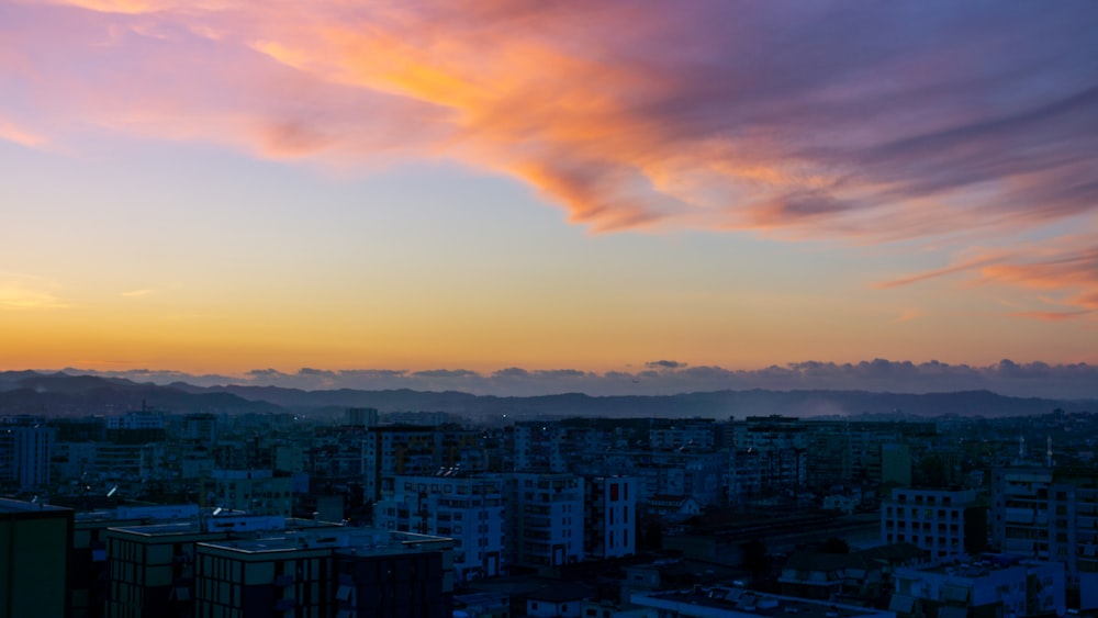 a view of a city at sunset with clouds in the sky