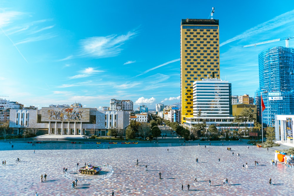 a group of people walking around a plaza in the middle of a city