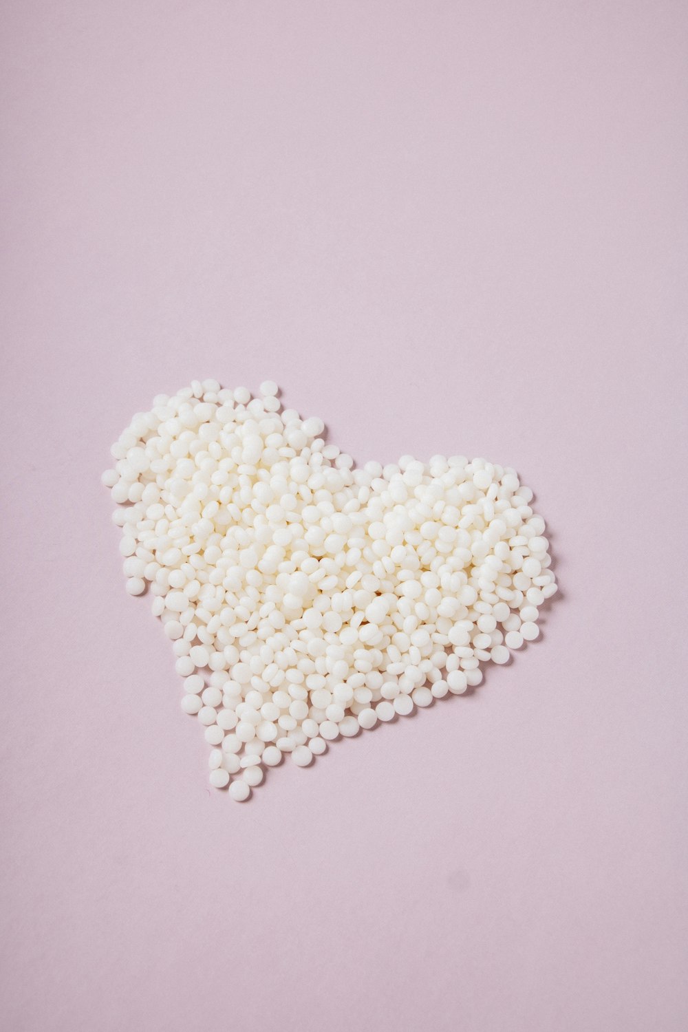 a pile of white pills in the shape of a heart