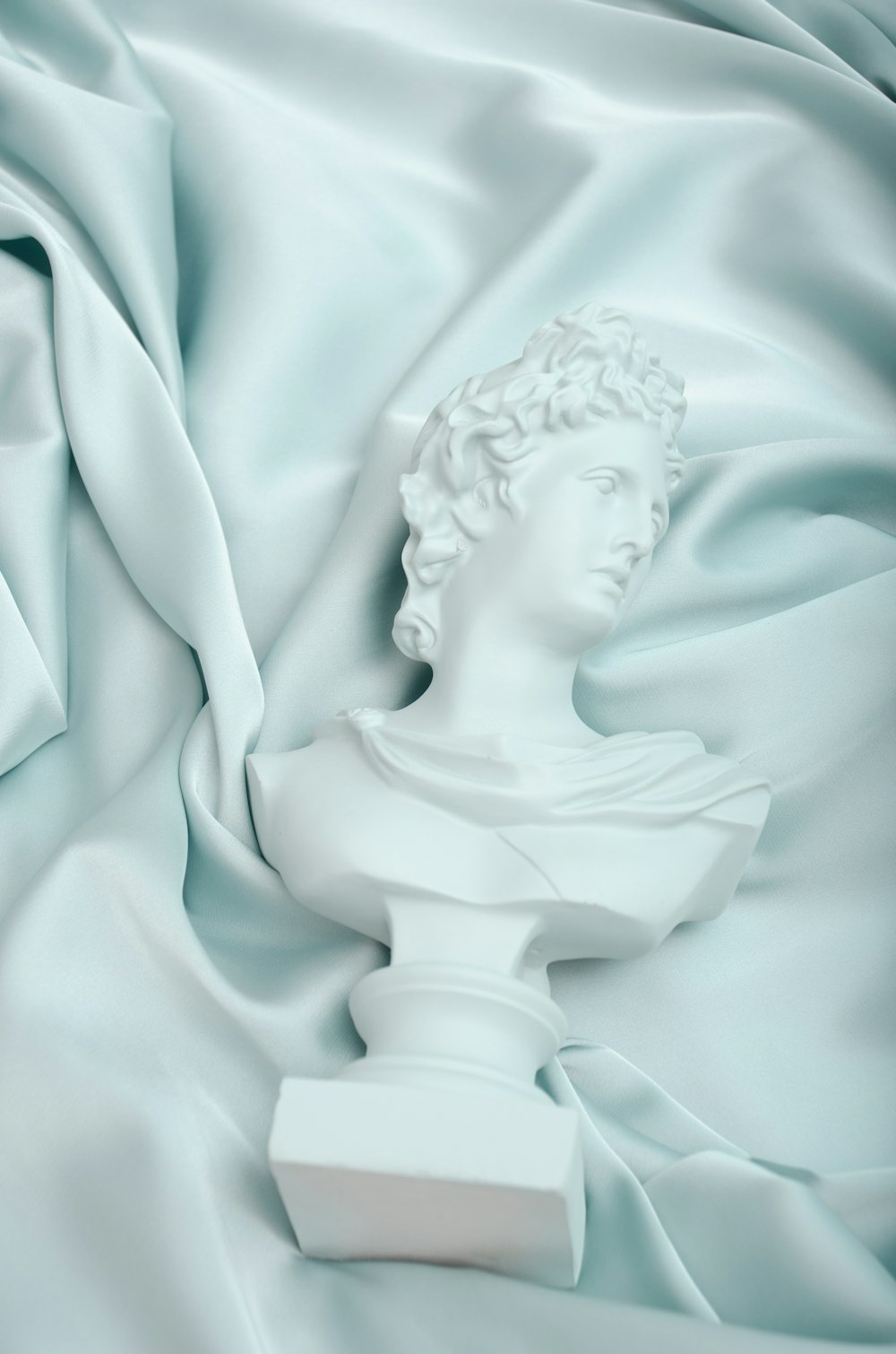 a white bust of a woman on a blue satin