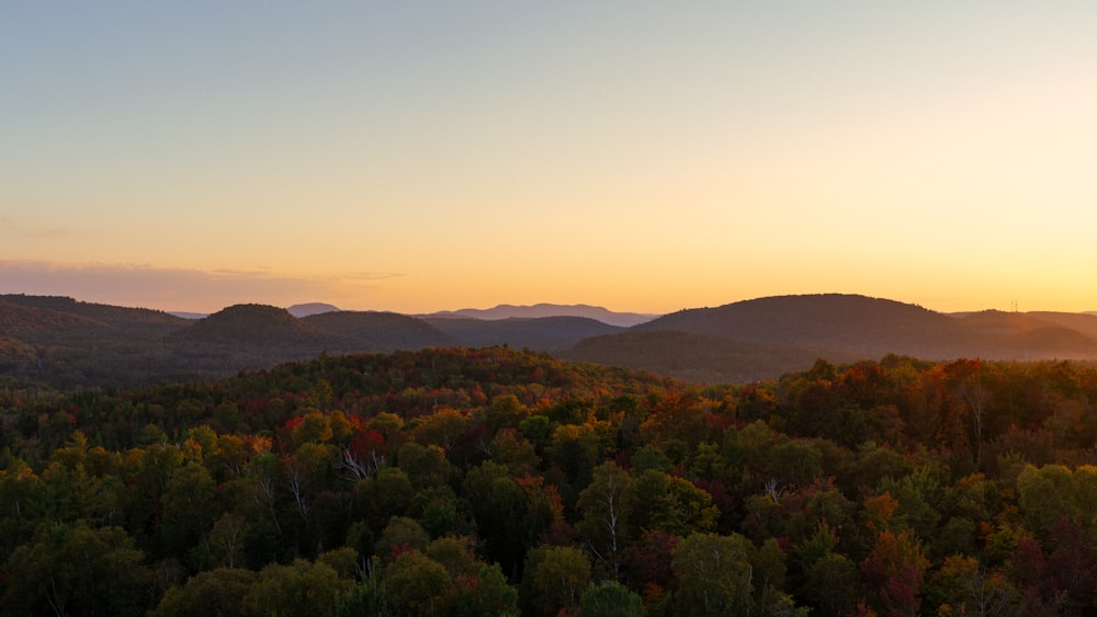 the sun is setting over the mountains and trees