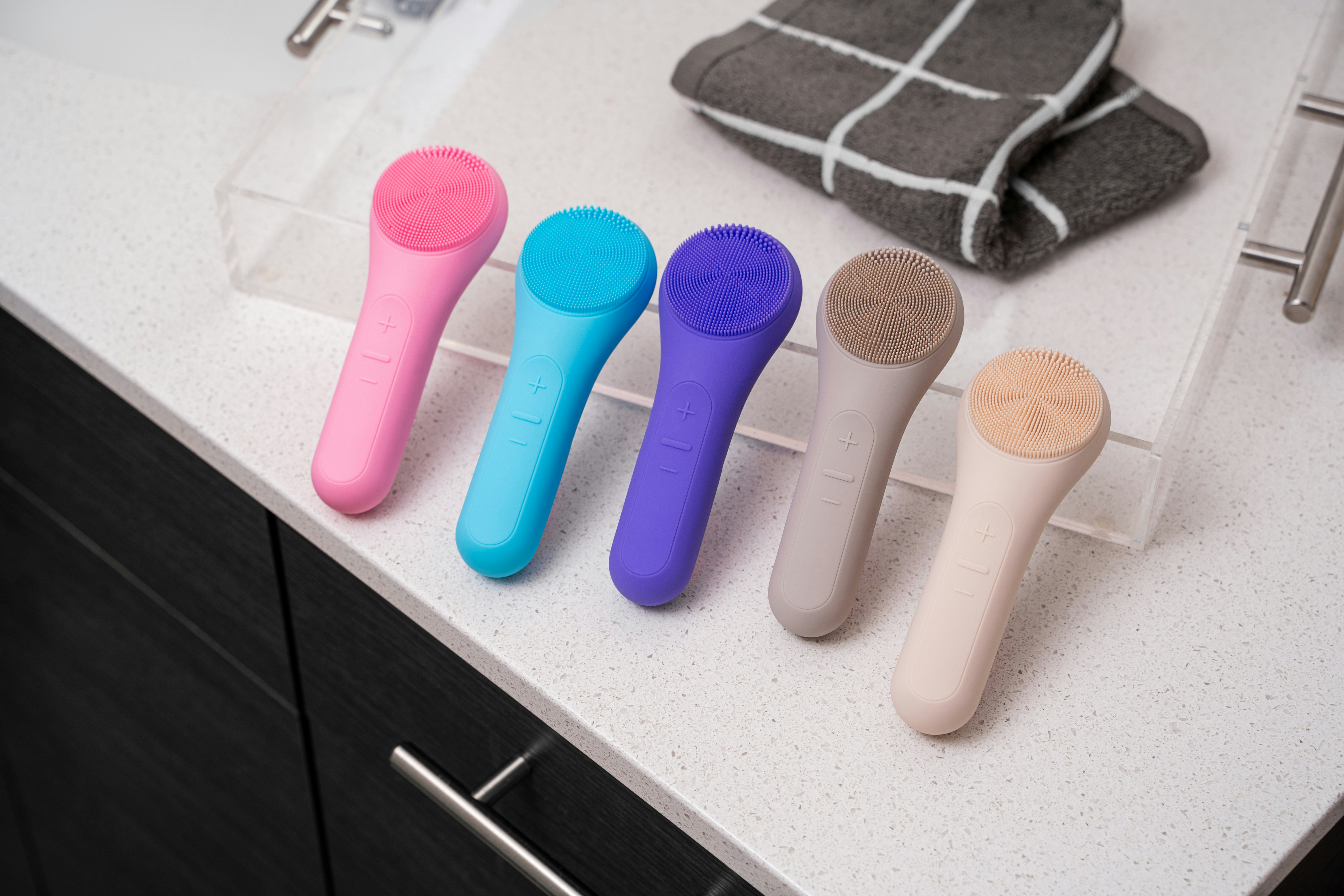 four different colored toothbrushes sitting on a counter