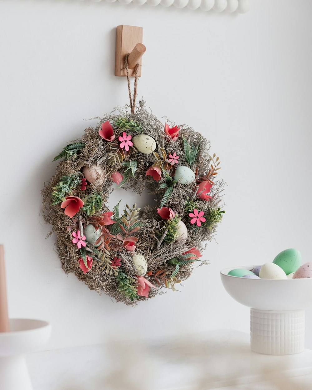 a wreath hanging on a wall next to a bowl of eggs