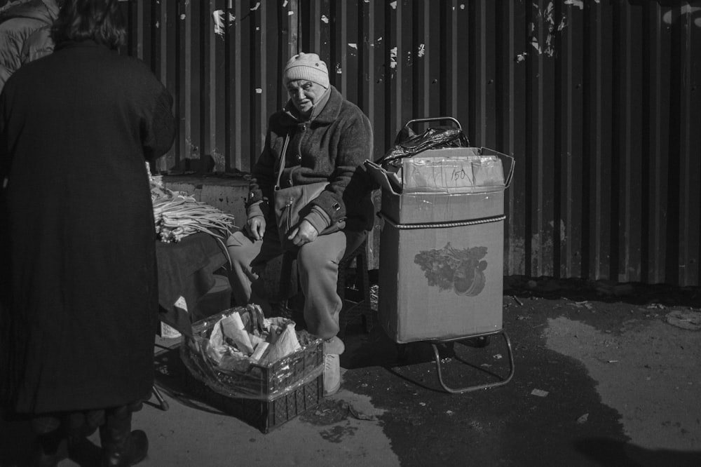 a black and white photo of a man sitting on a bench