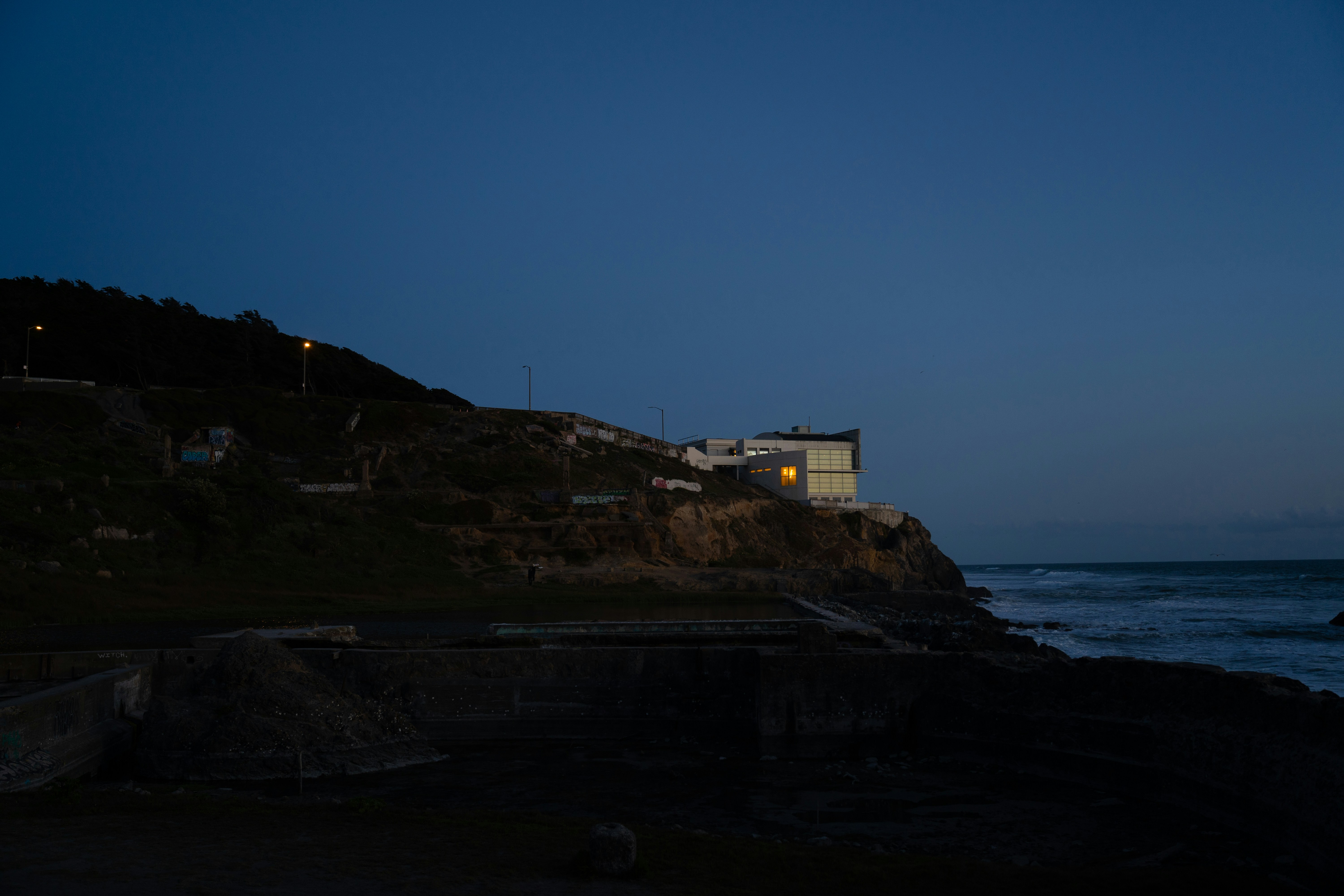 una casa seduta in cima a una scogliera vicino all'oceano