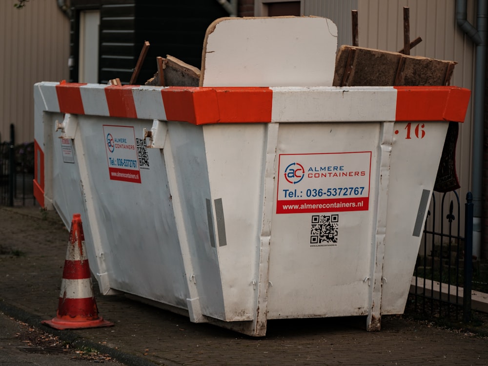 a dumpster sitting on the side of a road next to a traffic cone