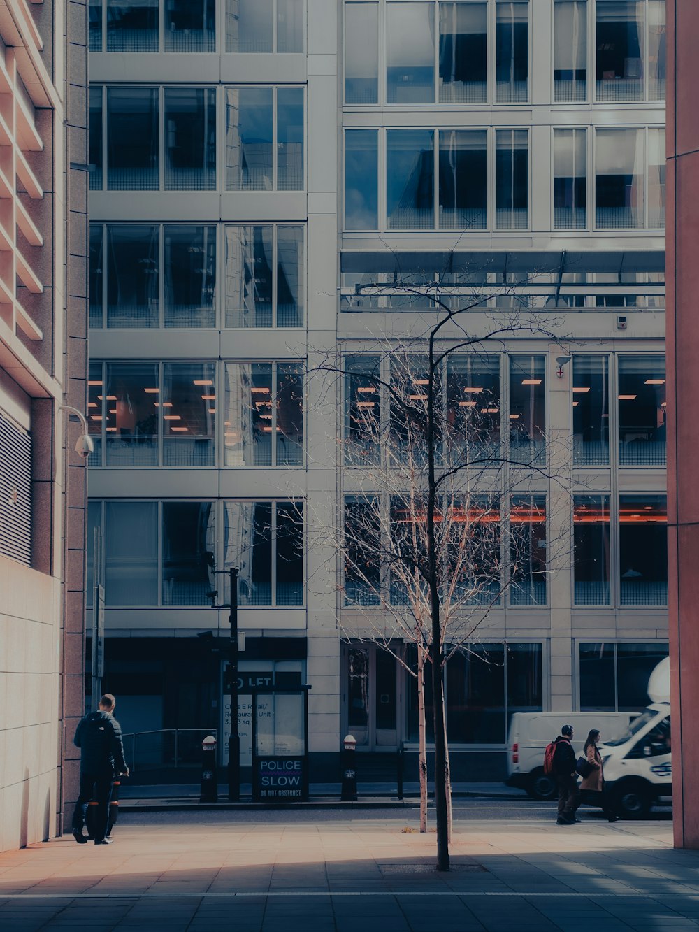 a tall building sitting next to a tree on a sidewalk