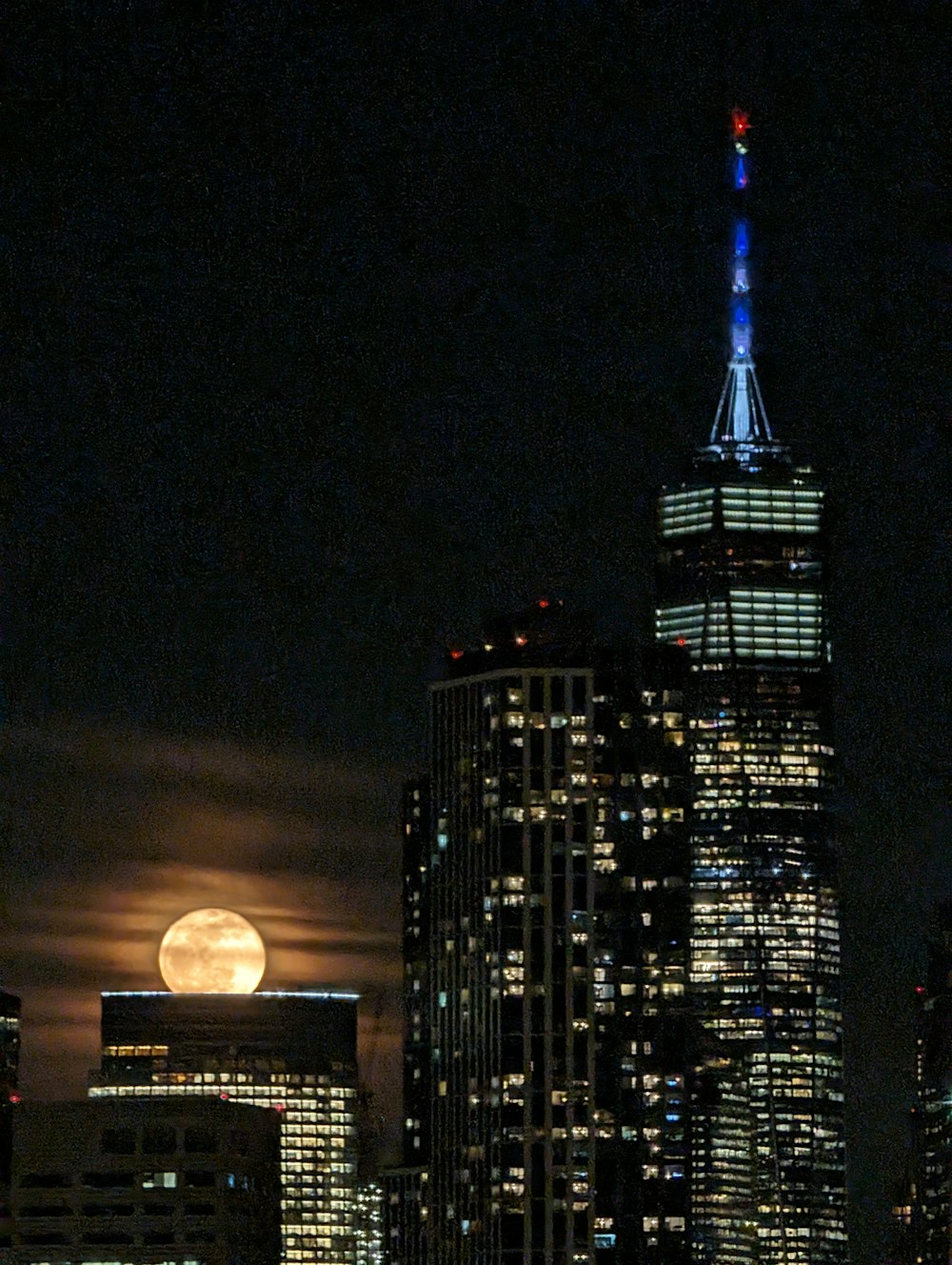 a full moon rises over a city at night