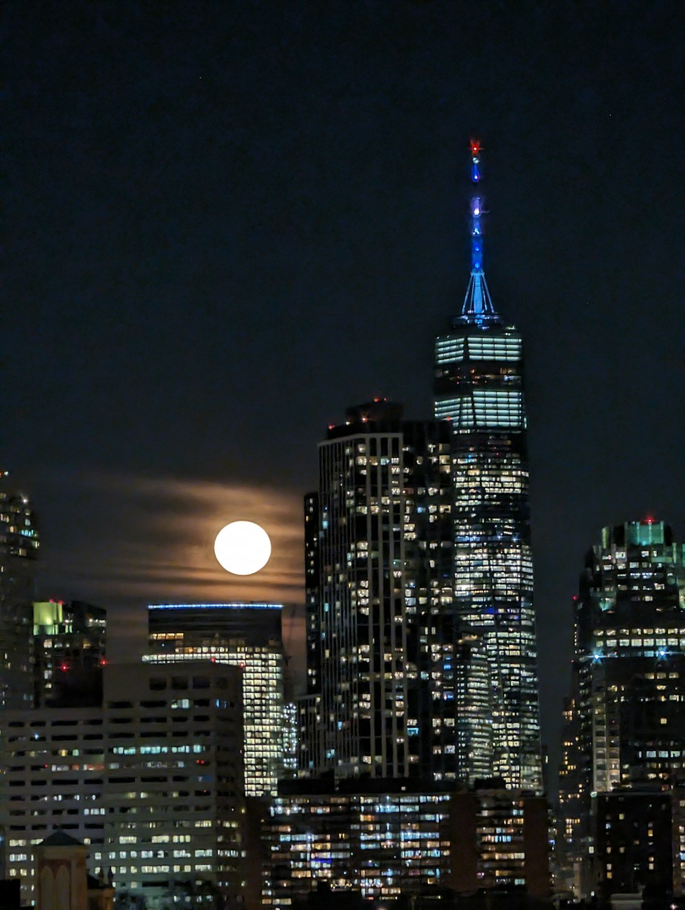 a full moon rises over a city skyline