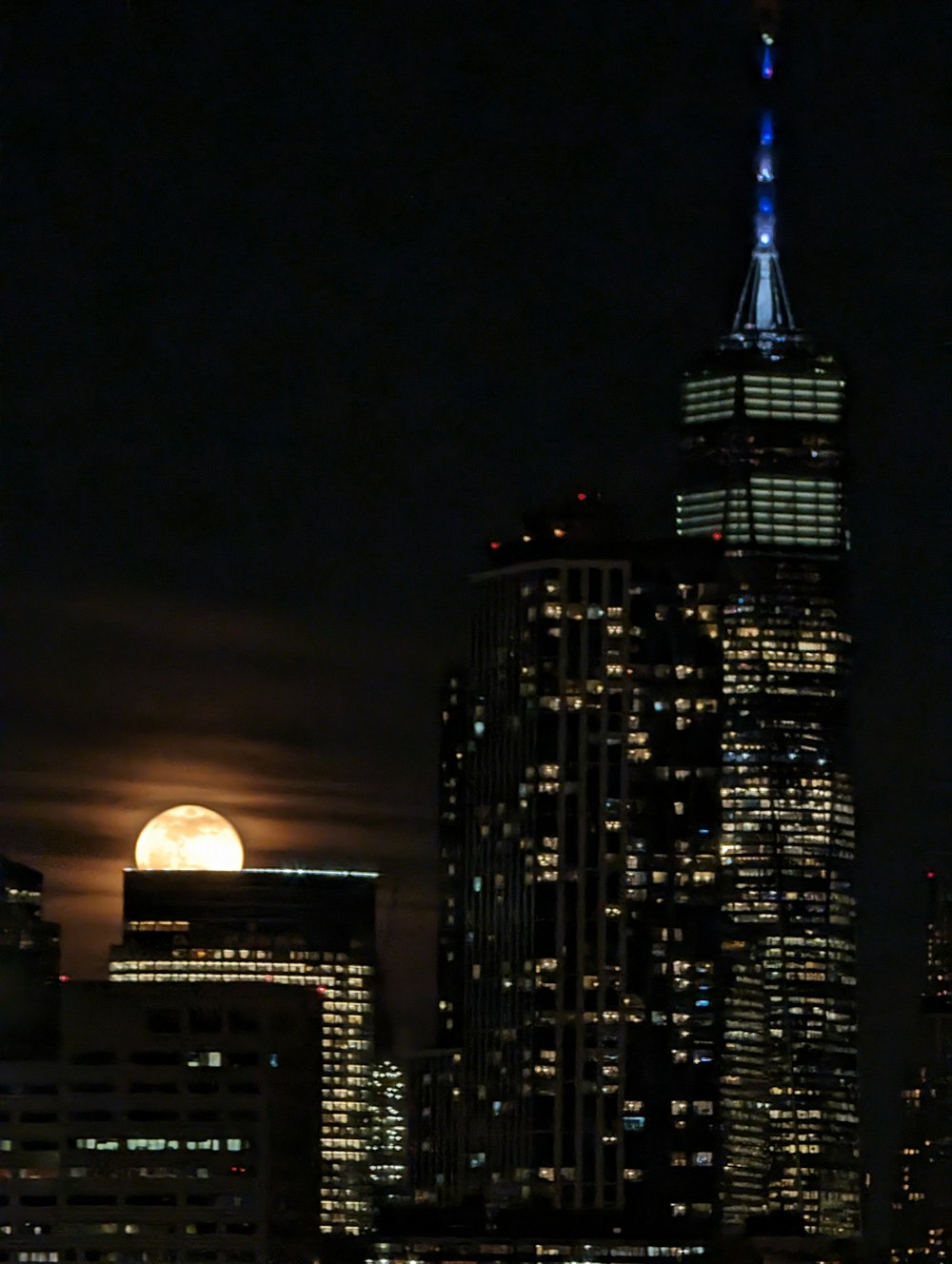 a full moon rises over a city at night