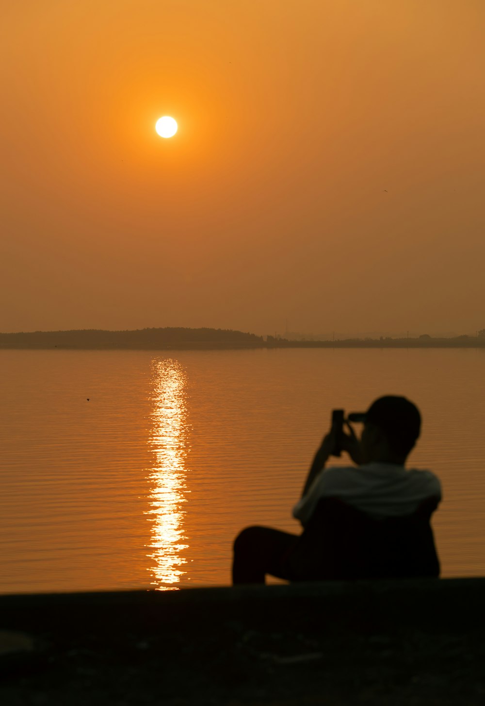 a man sitting on a bench watching the sun set