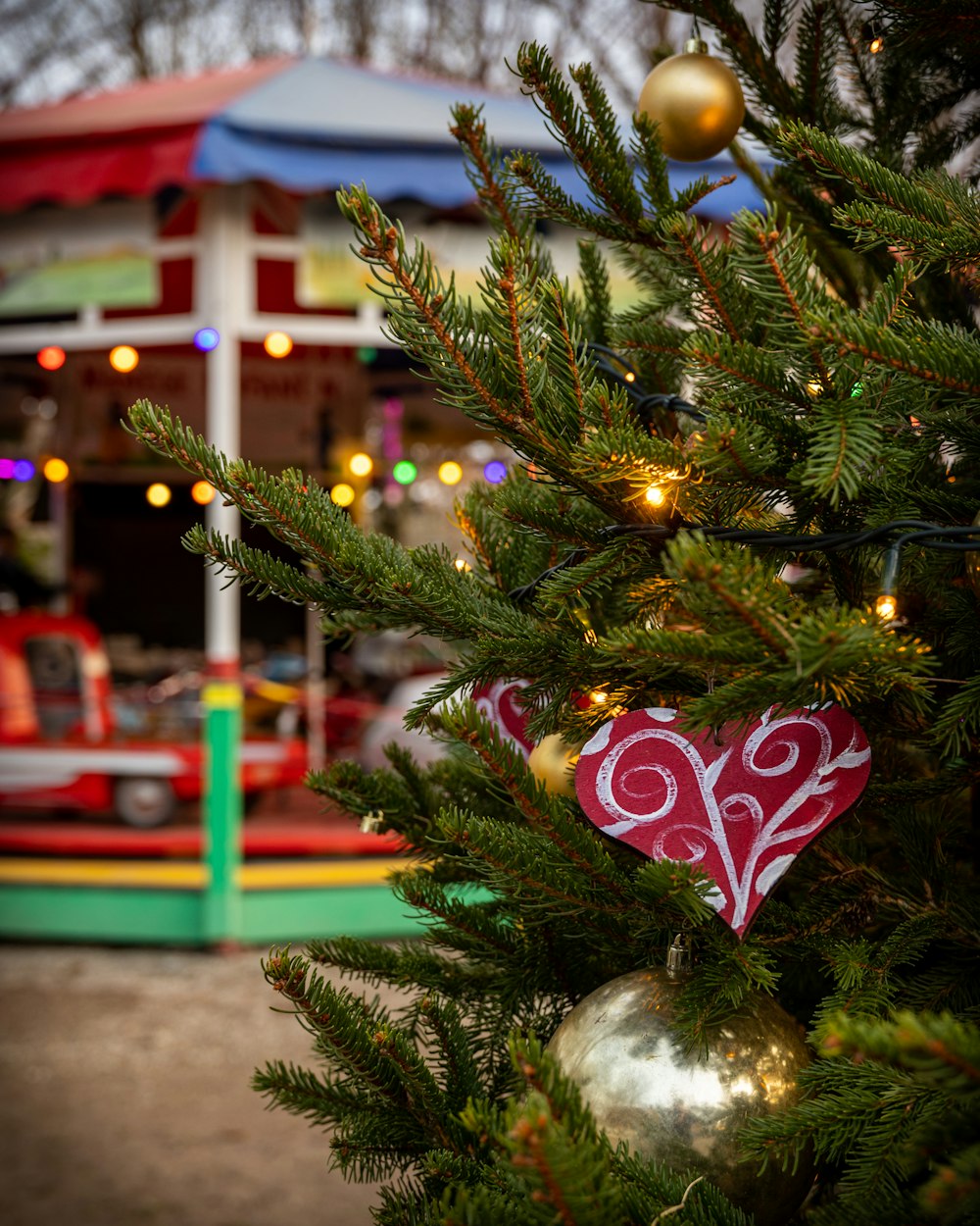 a close up of a christmas tree with a carousel in the background