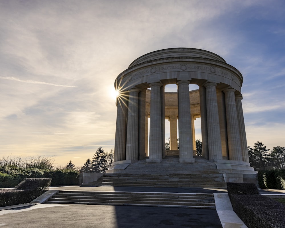 the sun is setting behind a monument in a park