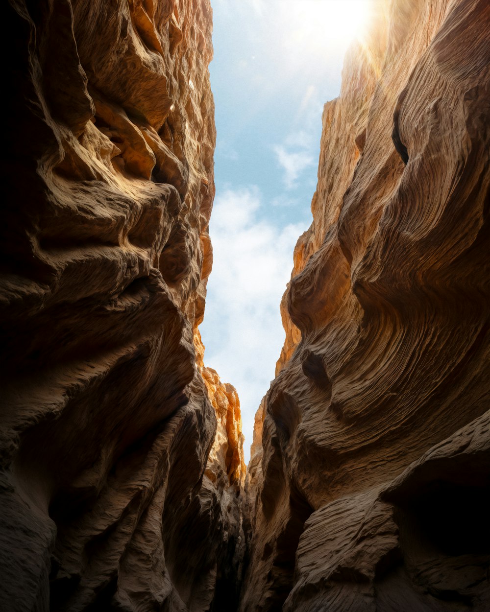 a narrow canyon with a bright light coming through it