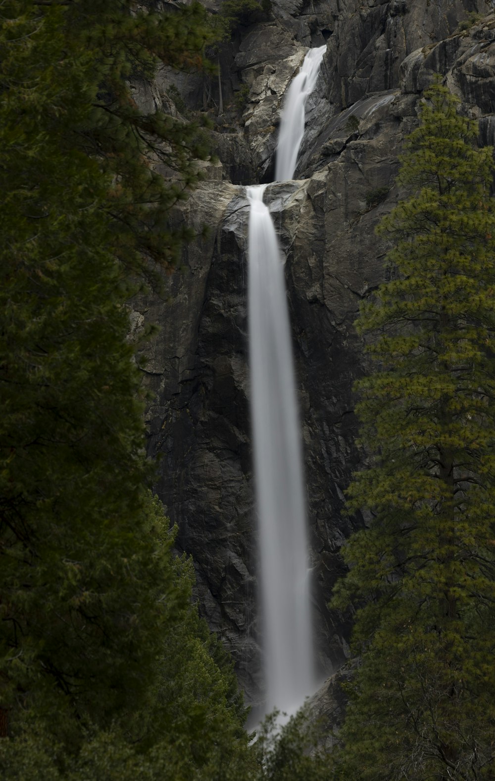 a tall waterfall is seen through the trees