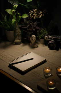 a table with a notebook, candles and a camera