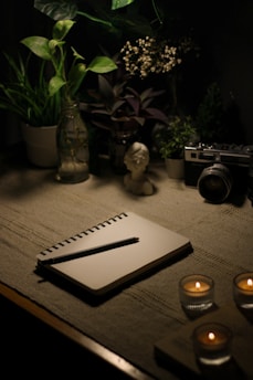 a table with a notebook, candles and a camera