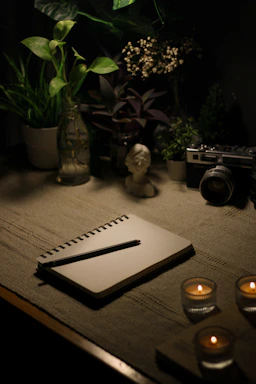 a table with a notebook, candles and a camera