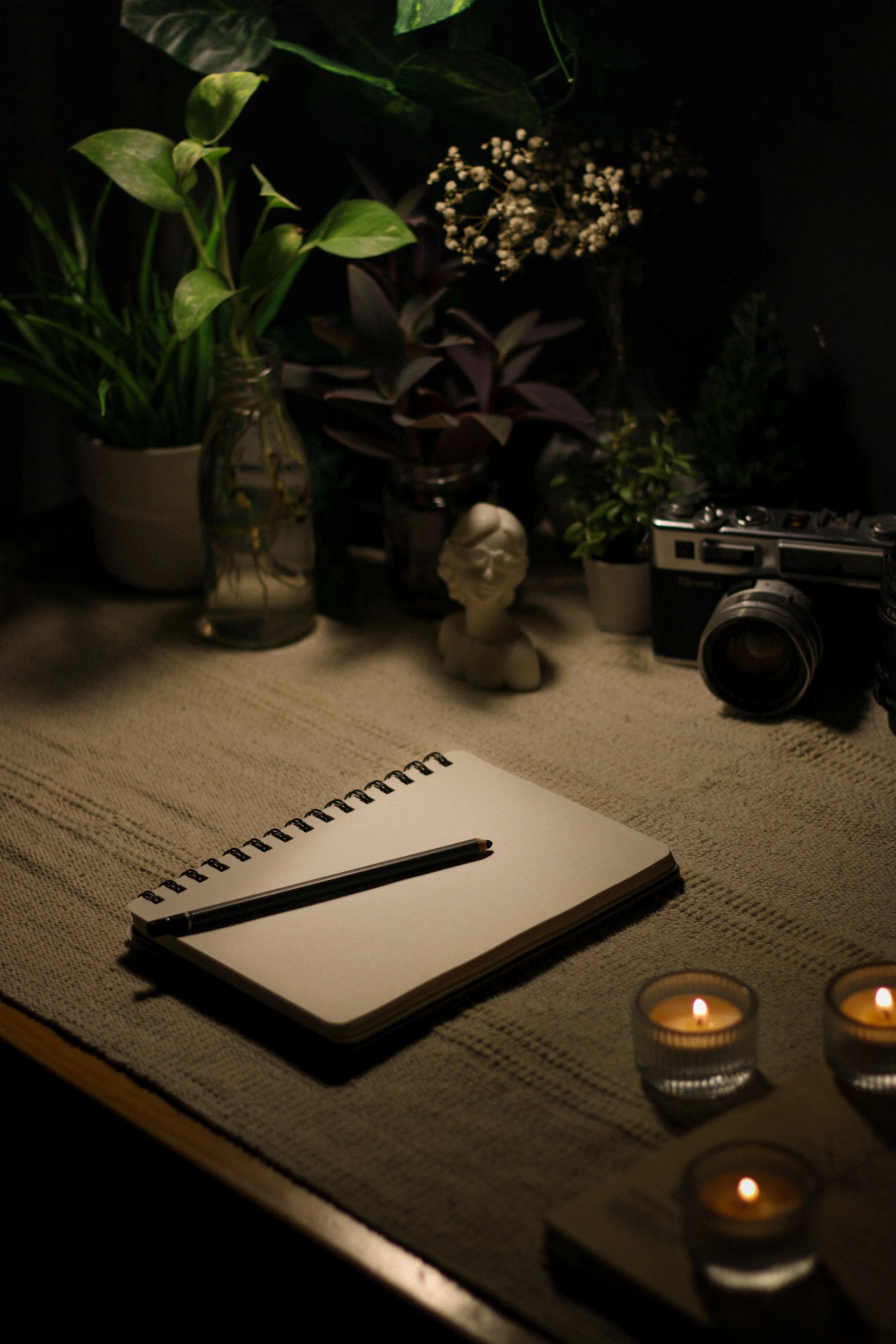 a table with a notebook, candles and a camera