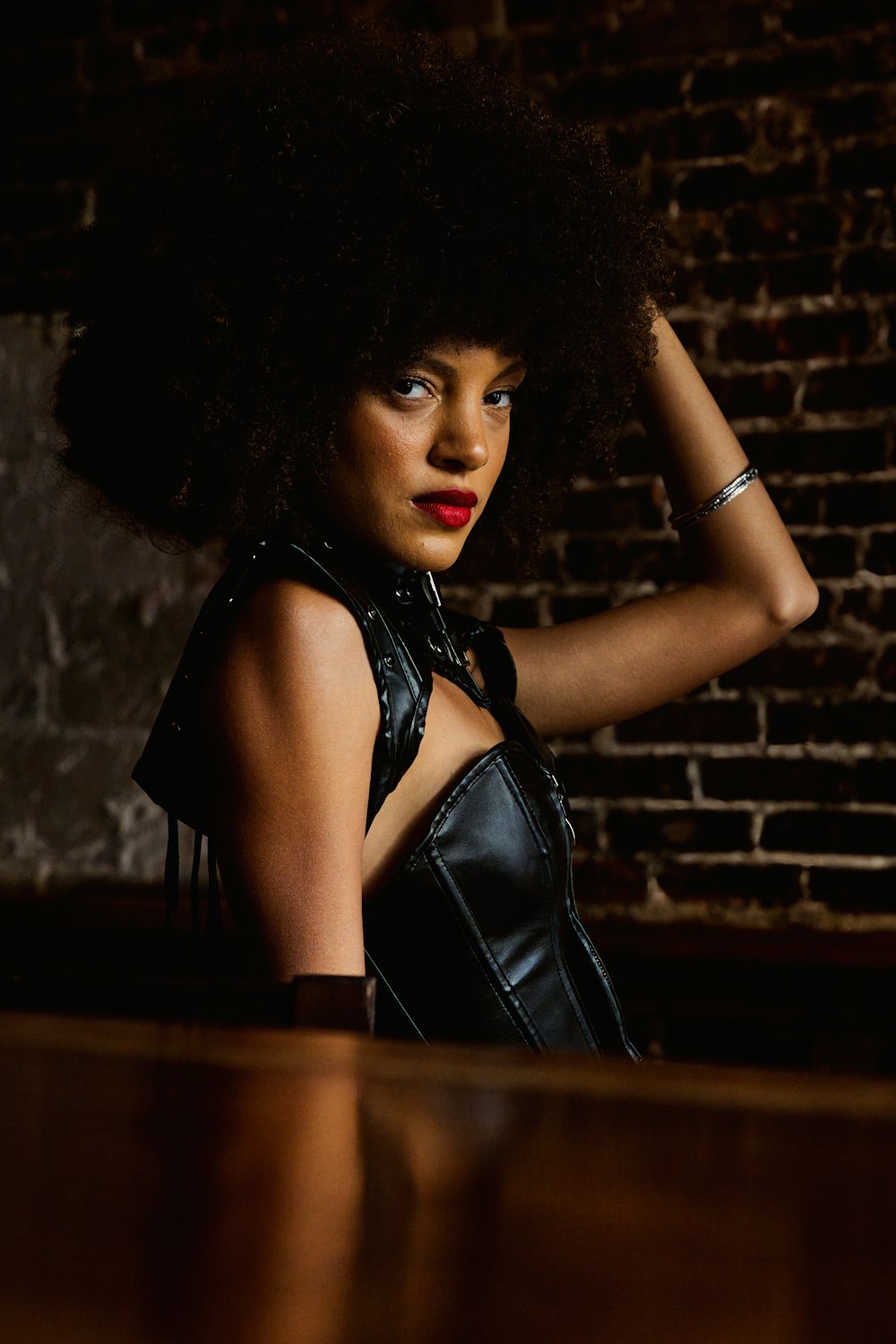 a woman with an afro standing in front of a brick wall