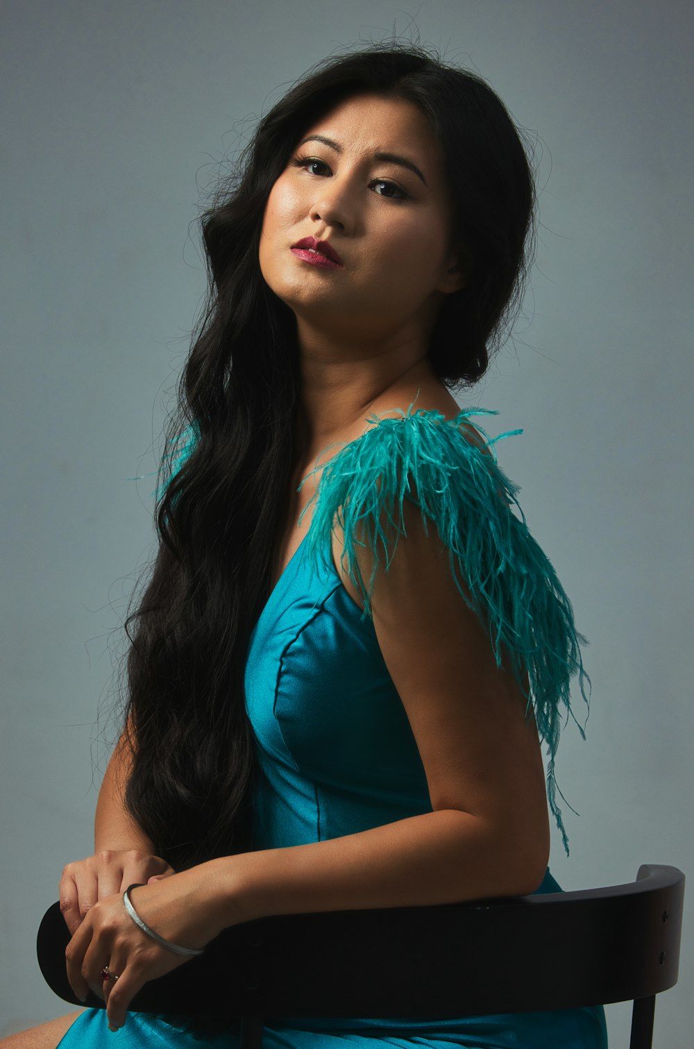 a woman in a blue dress sitting on a chair