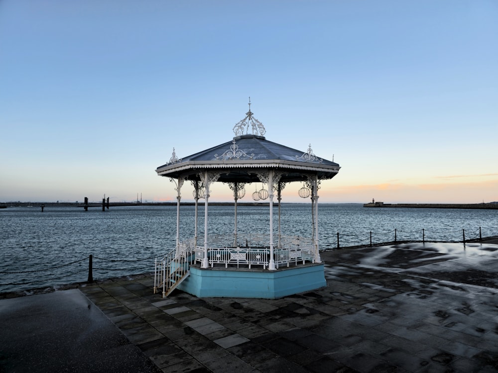 a gazebo sitting on top of a pier next to the ocean