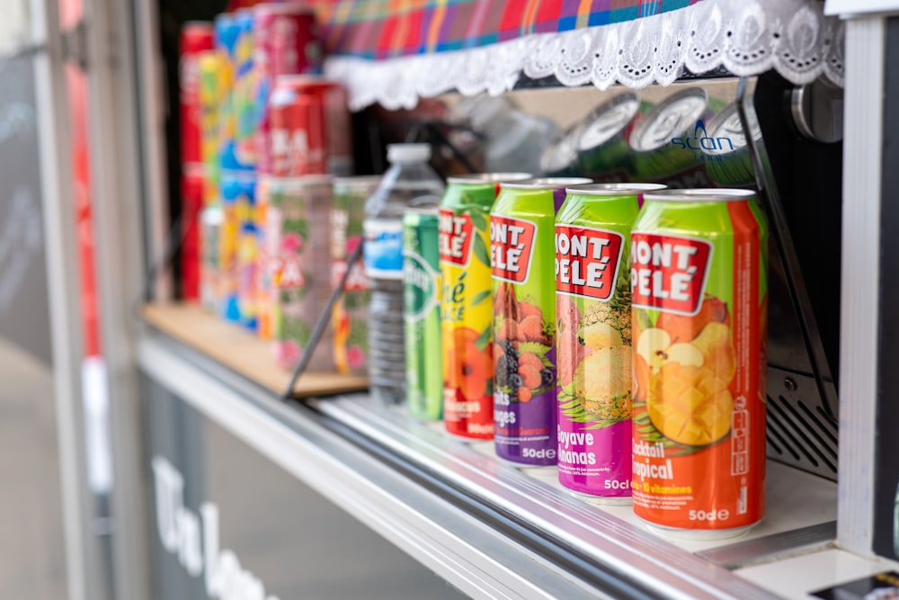 a row of soda cans sitting on top of a shelf