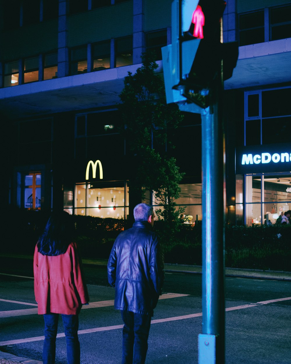 a man and a woman walking down a street at night