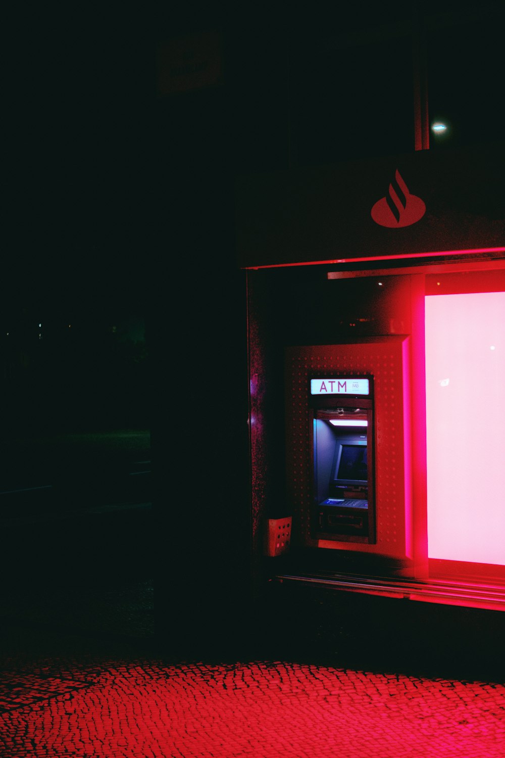 a red lit atm machine in a dark room