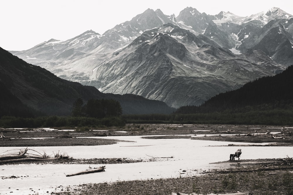 a man riding a horse across a river surrounded by mountains