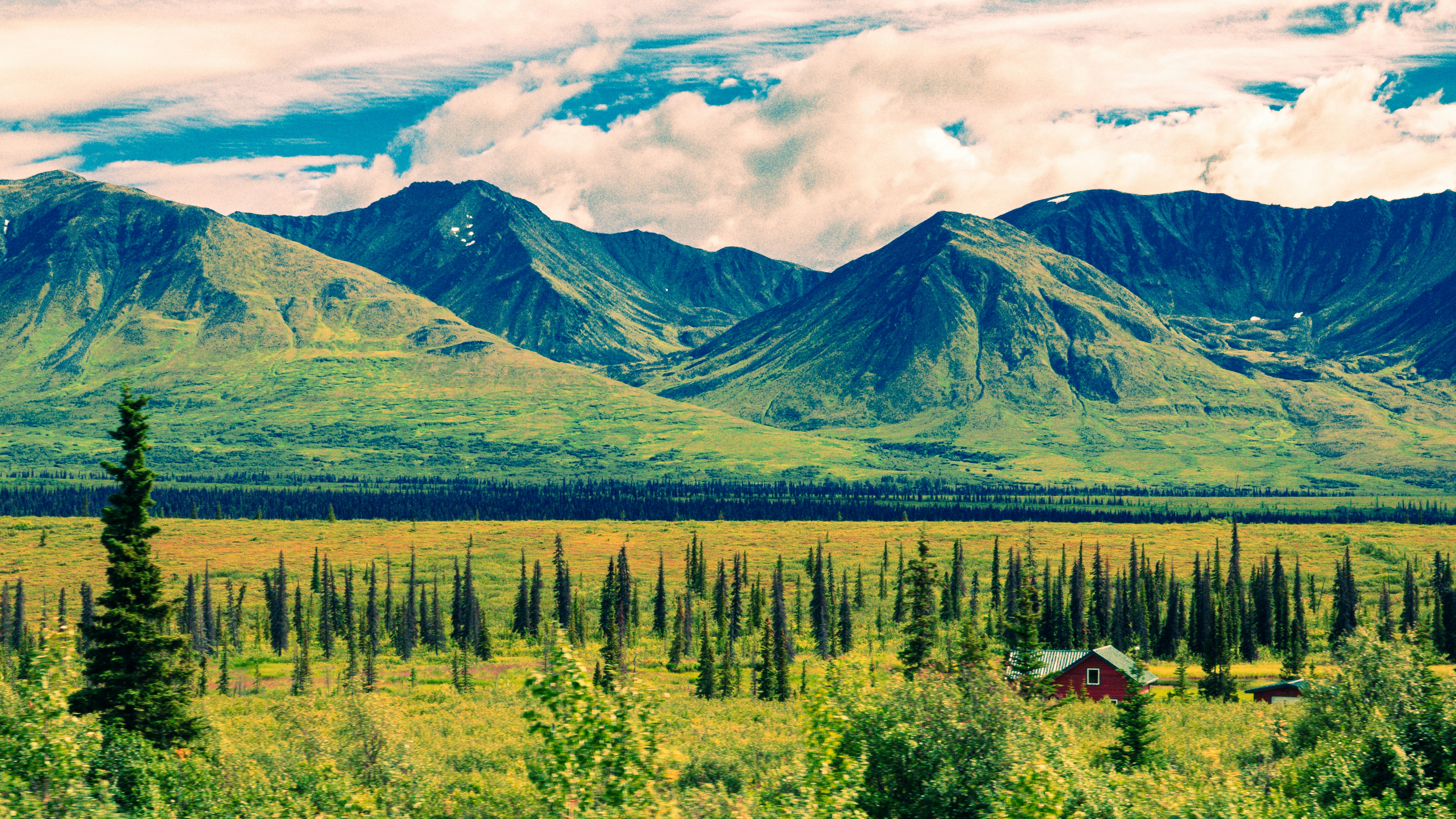 a scenic view of a mountain range with a cabin in the foreground