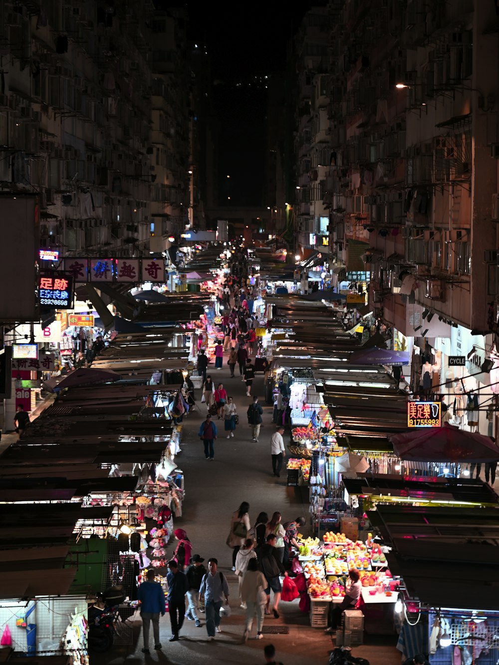 a crowded market area at night with people shopping