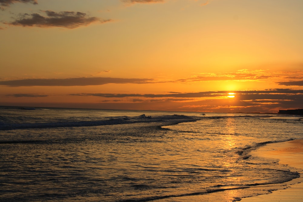 the sun is setting over the ocean on the beach