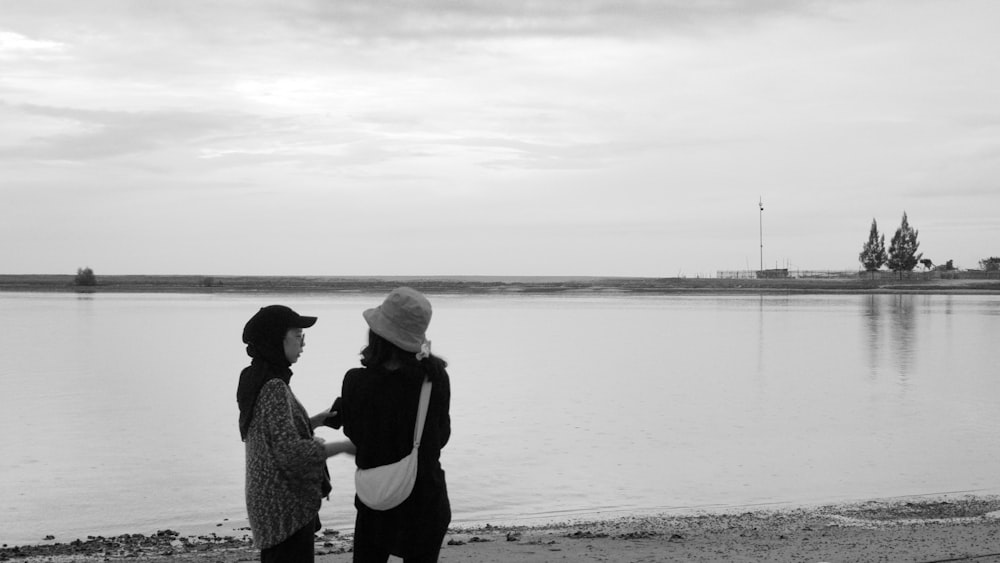 a couple of women standing next to a body of water