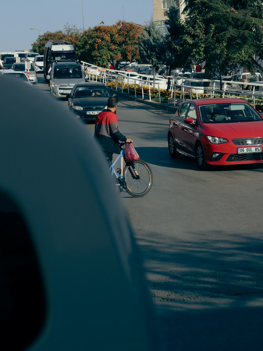 a man riding a bike down a street next to a red car