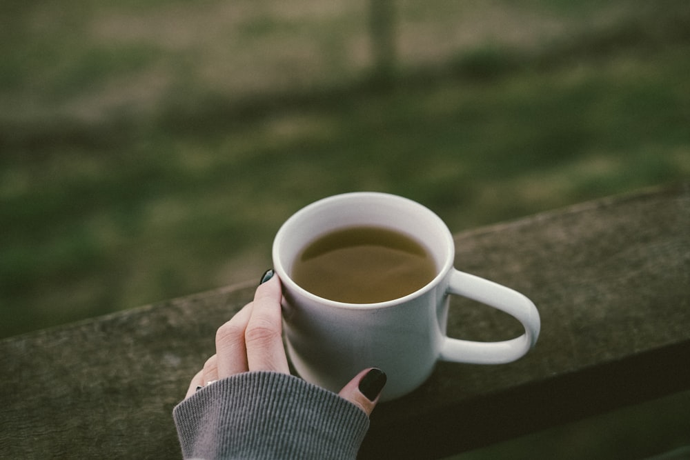 a woman's hand holding a cup of coffee