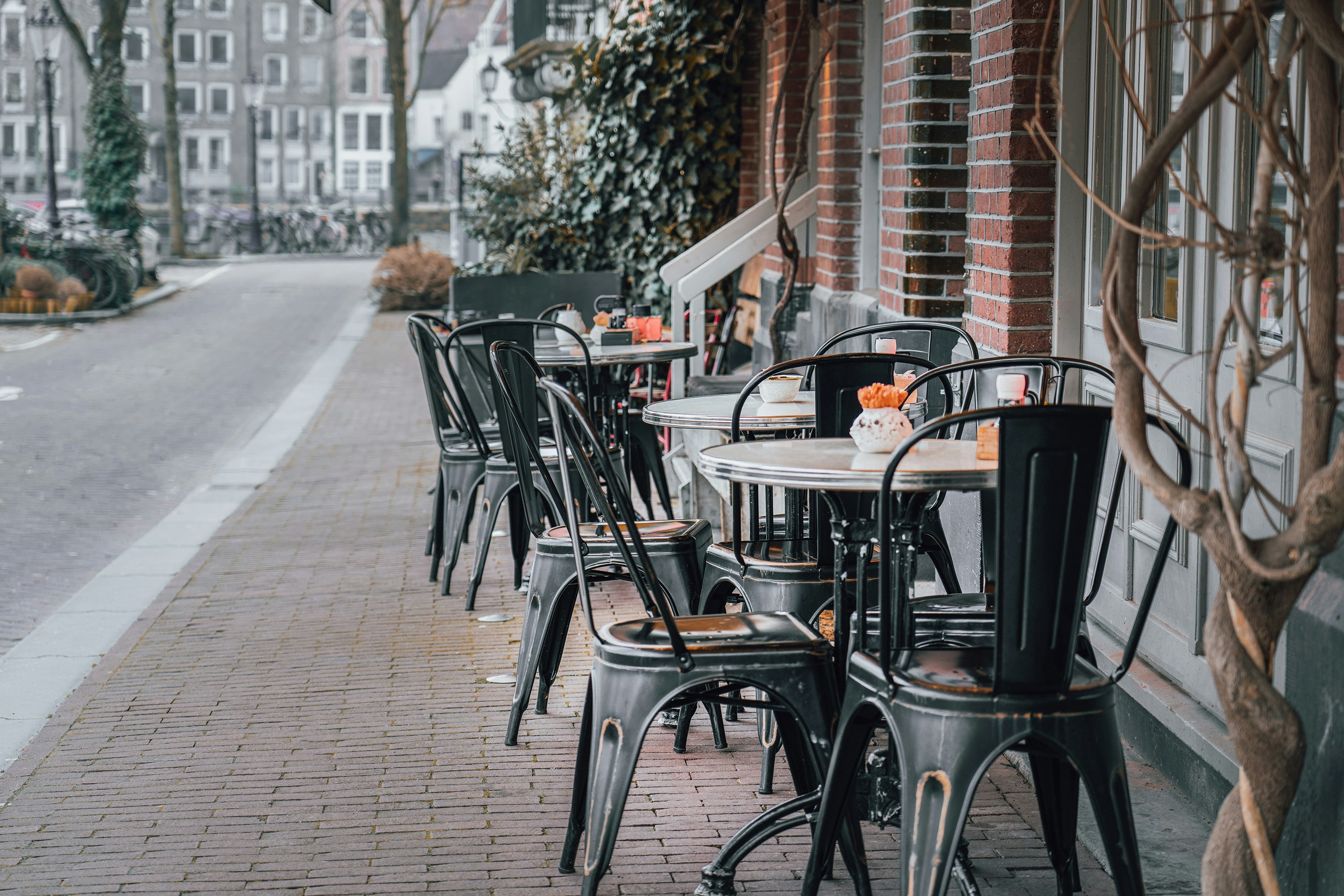 a row of tables and chairs on a sidewalk, restaurant table