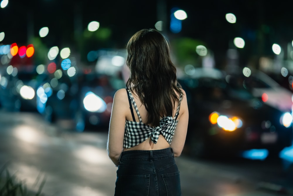 a woman standing on the side of a road at night