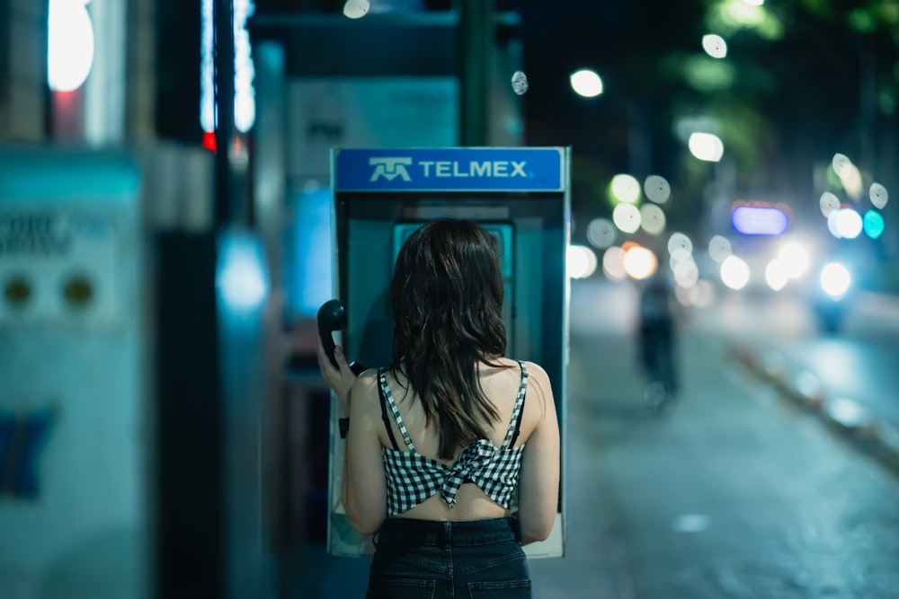 a woman standing in front of a telephone booth