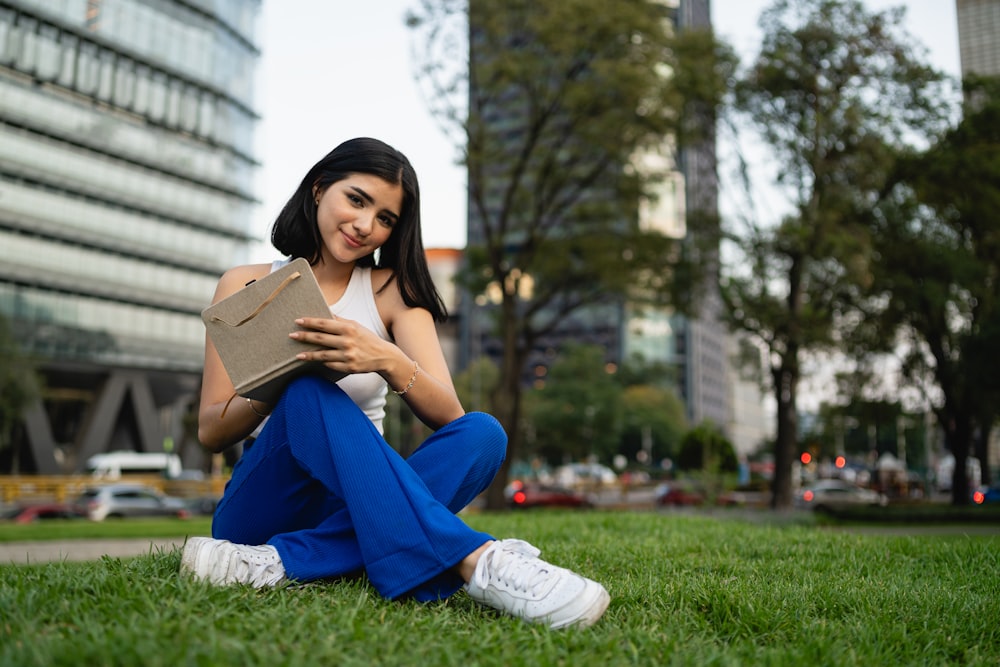 a woman sitting in the grass reading a book