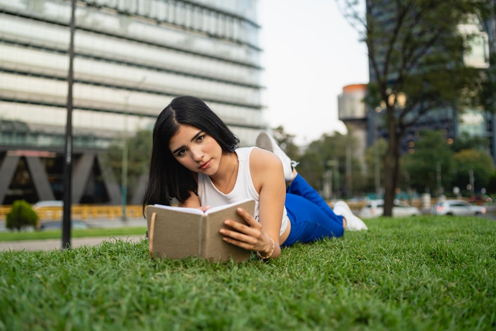 a woman laying on the grass reading a book