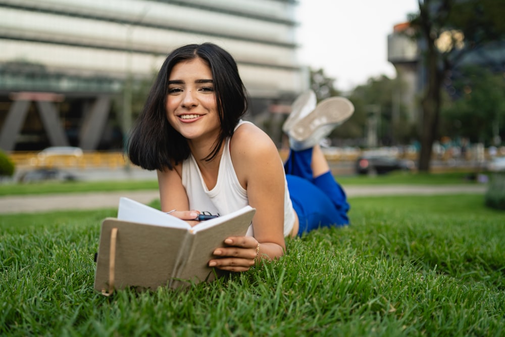 a woman laying on the grass reading a book