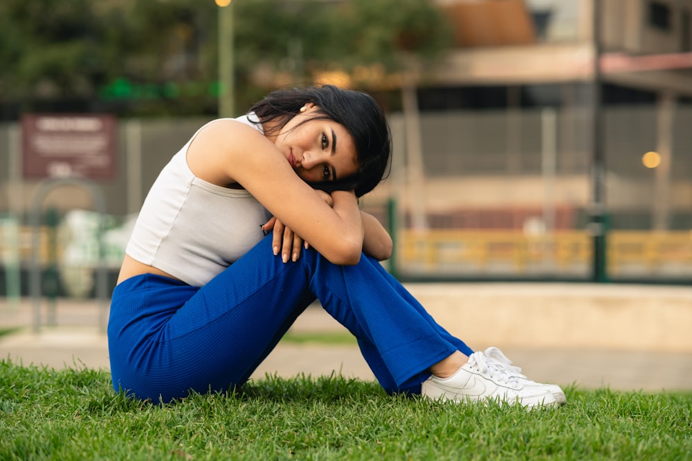 a woman sitting on the grass in a park