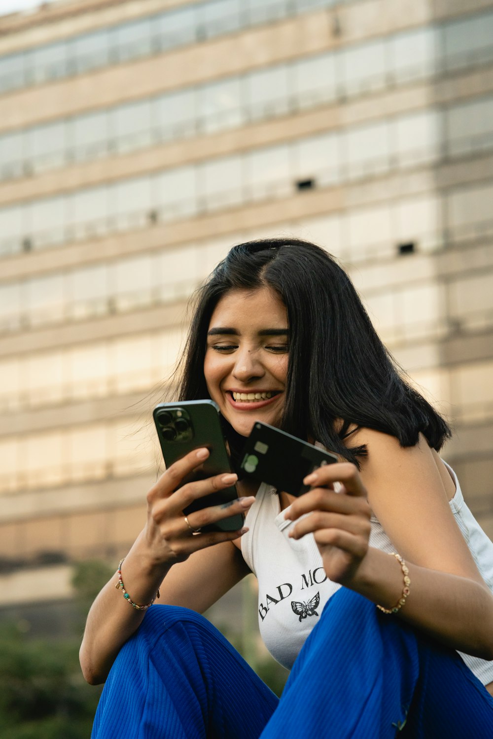 a woman sitting on the ground looking at a cell phone