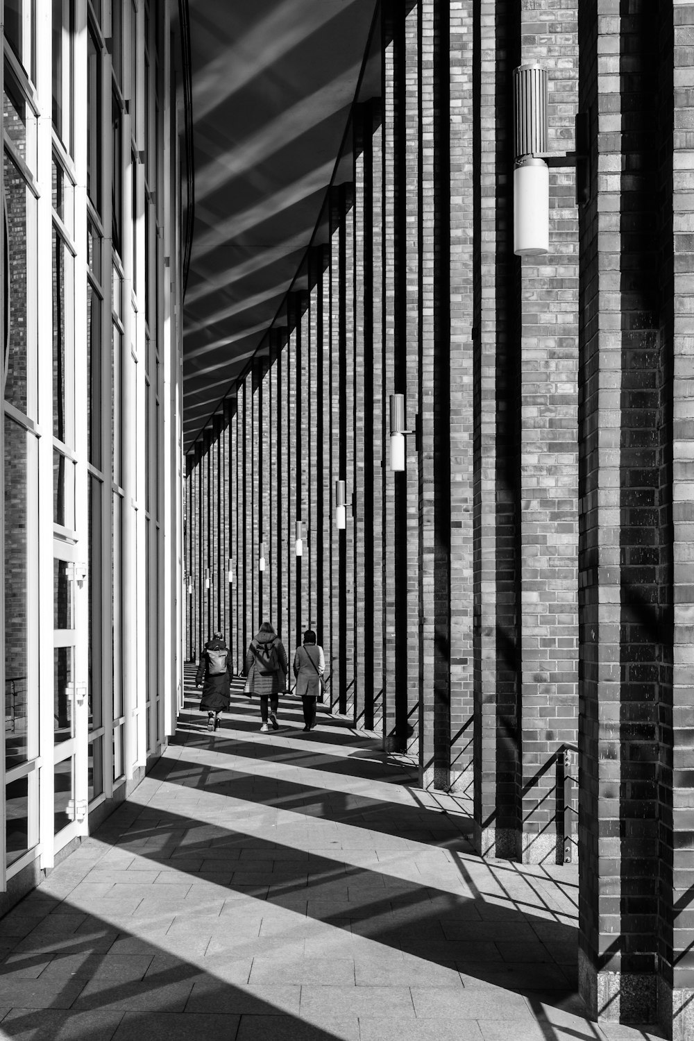 a black and white photo of people walking down a walkway