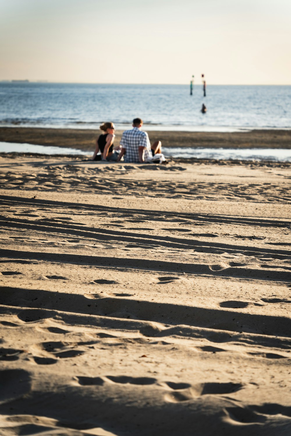 a group of people sitting on top of a sandy beach